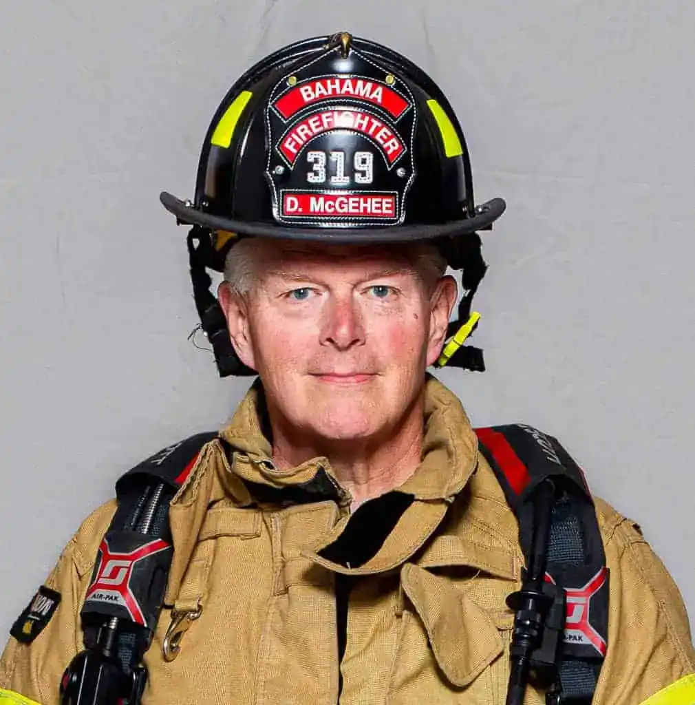 Douglass McGehee, firefighter with the Bahama Volunteer Fire Department, in full turnout gear and a black helmet labeled “Firefighter 319,” facing forward for an official portrait.