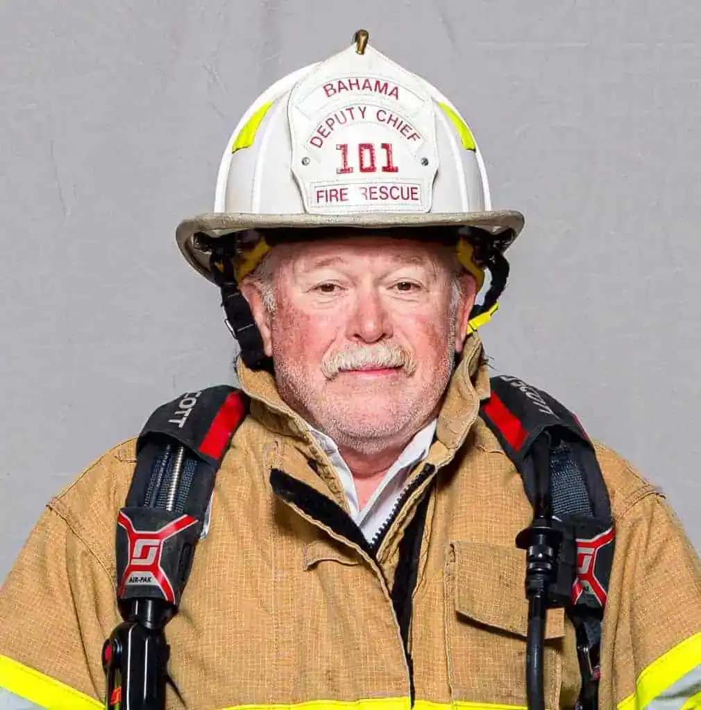 Dale Ellis, Deputy Chief of the Bahama Volunteer Fire Department, in full turnout gear and helmet labeled “Deputy Chief 101,” posing for a professional portrait.