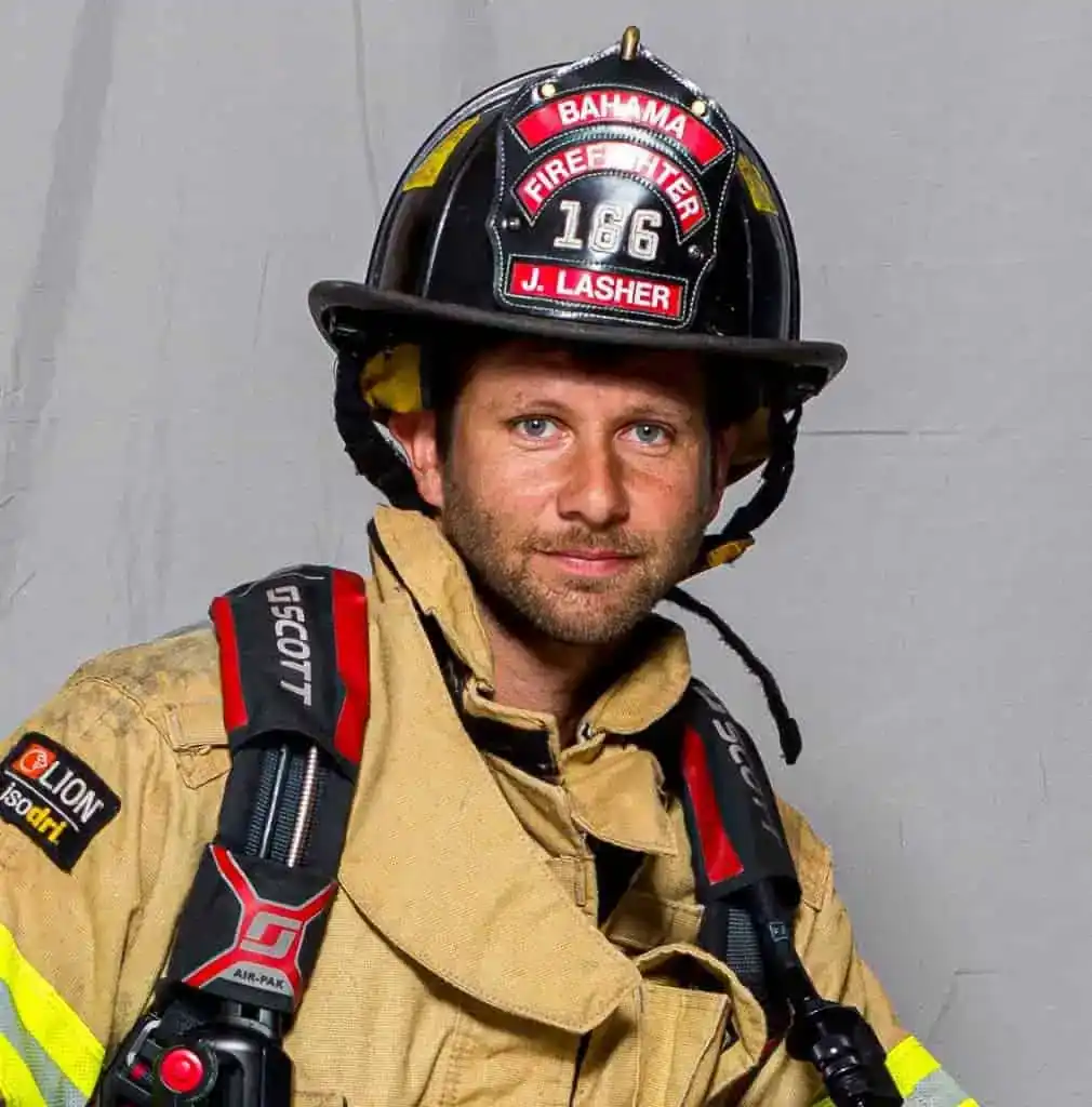 John Lasher, firefighter with the Bahama Volunteer Fire Department, in full turnout gear and a black helmet labeled “Firefighter 186 J. Lasher,” posing for an official portrait.