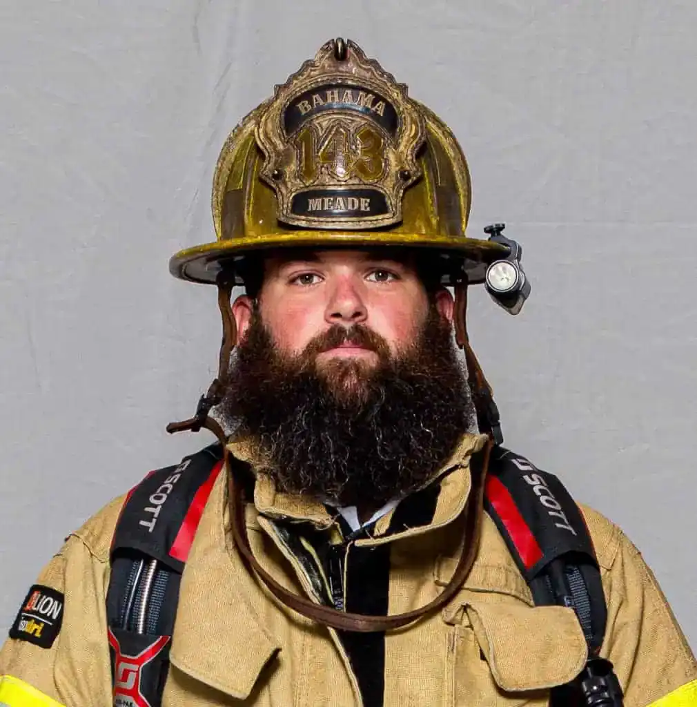 Harrison Meade, Lieutenant of the Bahama Volunteer Fire Department, in full turnout gear and a gold helmet marked “143 Meade,” posing for a formal portrait.