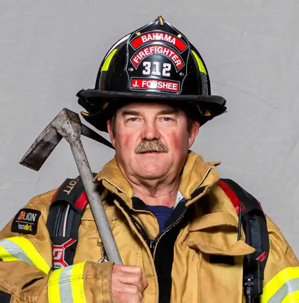 David Weatherspoon, Assistant Chief of the Bahama Volunteer Fire Department, in full turnout gear and a white helmet with a gold "Assistant Chief" shield, posing for a formal portrait.